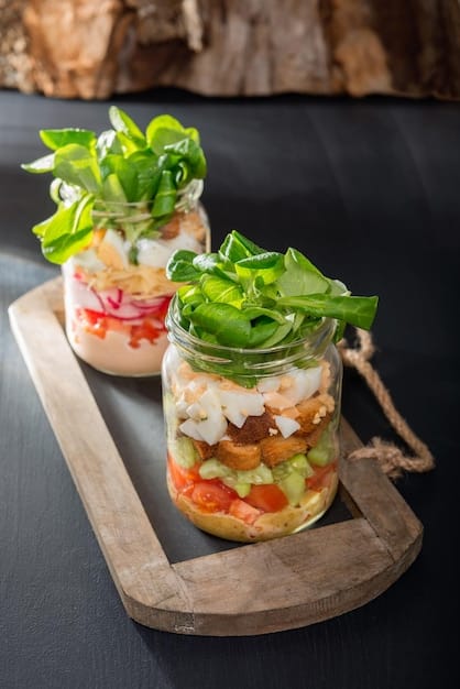 A bright and colorful shot of a variety of healthy salad jars, each layered with different vegetables, grains, proteins, and dressings, displayed neatly on a kitchen counter to showcase meal prep ideas.