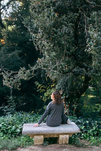 A serene person meditating outdoors in a peaceful garden, surrounded by lush greenery and sunlight.