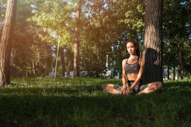 A person sitting peacefully in a yoga pose outdoors, surrounded by lush greenery and soft sunlight. The scene evokes tranquility, inner peace, and physical well-being.