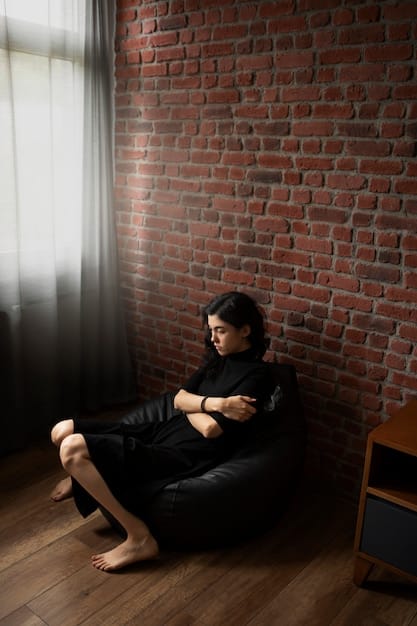 A person sitting alone in a dark room, hugging their knees, symbolizing the isolation and withdrawal often associated with trauma and mental health conditions like depression and anxiety.
