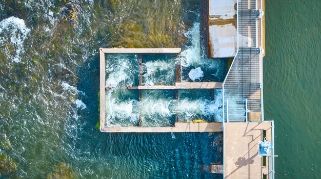 An aerial view of a modern hydroelectric dam, showcasing the powerful flow of water through the turbines. The landscape surrounding the dam is lush and green, illustrating the natural integration of hydroelectric power with the environment.