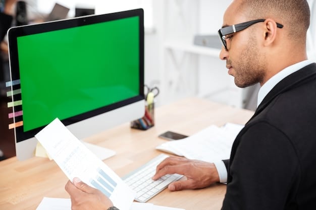 A close-up of a business owner reviewing financial documents in their office. The office is modern and well-lit, with a computer screen displaying a spreadsheet.